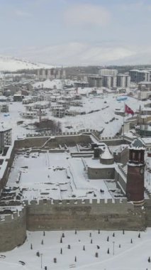 Karların altında Erzurum kentinin insansız hava aracı görüntüsü, Erzurum 'un tarihi kalesinin kış manzarası, taştan kale duvarları ve dalgalı Türk bayrağı