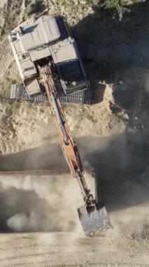 Toprak manzaralı kamyonları yükleyen kazıcı, bir çöp kamyonuna kum yükleyen kazıcı, taş ocağında çalışan, yerden yükselen toz, insansız hava aracı ateşi.