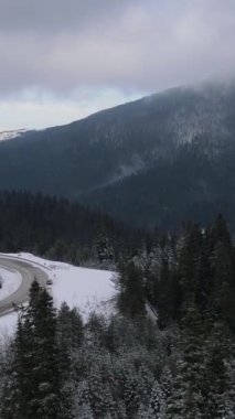Karla kaplı dağ sıralarının ve içinden geçen yolların drone görüntüsü, dağın yamaçlarında karın nasıl şekillendiğinin kış görüntüleri.