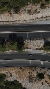 Geniş açı keskin viraj otoyolu, ormandaki kıvrımlı otoyol erişim yolundan geçen araçların hava aracı görüntüsü.