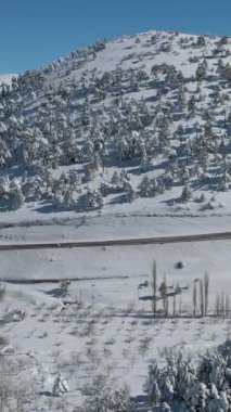 Karla kaplı dağın içinden geçen otobanın insansız hava aracı görüntüsü, kışın ulaşımın devam ettiği ana yollar.