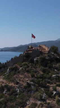 Zirvedeki gözetleme kulesinin drone görüntüsü, Türk bayrağının dalgalandığı tarihi kalıntılar, Simena Kalesi 'nde dalgalanan bayrağın görüntüsü.