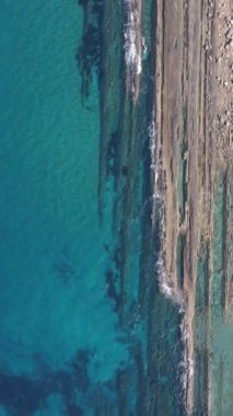 Drone view of the crystal clear sea waters of Kyrenia, turquoise color of the open sea, rocks and the natural beauty of cyprus with waves crashing on the beach