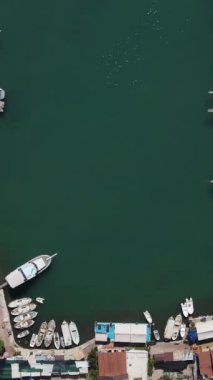 Sahil şeridinden limana giden insansız hava aracı görüntüsü, sahil yerleşiminden limandaki teknelerin hava görüntüsü.