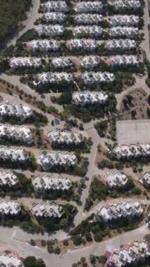 Tatil alanı manzarası, içinde çam ağaçları ve beyaz evler olan bir orman. İHA ile kuş bakışı görüş