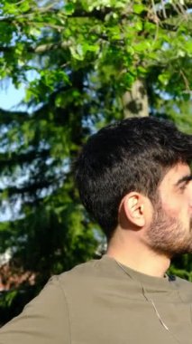 Sakallı delikanlıların ağaçların yanında oturup konuştuğu, gençlerin birbirleriyle sohbet ettiği yakın plan çekimler.