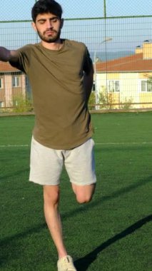 Genç bir adamın spor yaparken dizlerini halıda tek tek kaldırması ve antrenmandan önce ısınması ön planda.