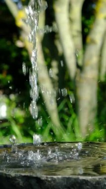 Parkta duran eski çeşmenin el yıkama manzarasını kapatın. İnsanlar parktaki fıskiyeden yararlanıyorlar.