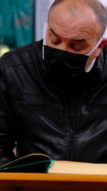 Yüzünde siyah bir maske olan, Kuran okuyan, camide İslam 'ın kutsal kitabını okuyan yaşlı bir adamın önü.