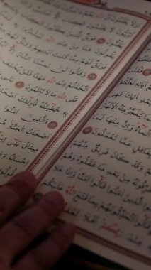 İslam 'ın kutsal kitabının ardından el üstünde duran adamın farklı bir açıdan çekilmiş resmi. Kuran' ın alfabesi Arapça.