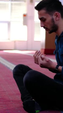 Mescid 'de oturup dua eden müslüman gençlerin yan görünüşü. Dua eden adam duasını bitirdiğinde ellerini yüzüne sürterek dua eder.