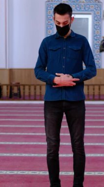 Camiye farklı açılardan tapan maskeli genç adam, camide dua eden Müslüman erkekler, İslam 'a inanan insanlar Tanrı' ya dua ediyorlar.