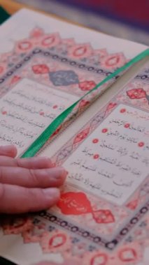 İnsanoğlunun eli, Arap alfabesindeki kutsal İslam kitabı olan açık yeşil Kur 'an' ın sayfalarını karıştırıyor.