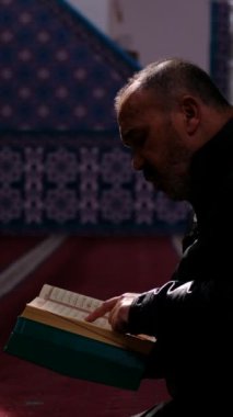 (Bu adam), Mescid-i Haram 'da oturmuş, yanında Kur' an 'ı okuyan ve içinde 