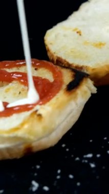 Hamburgerin yarısının üzerine ketçap sıkarken, hamburger soslu fast food hazırlarken, ekmeğin üzerine sıvı soslar dökerken,