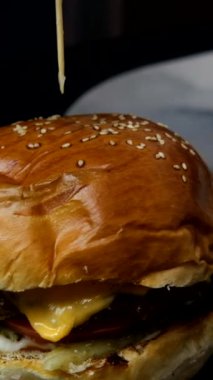 Yumuşak bir hamburgerin içine çubuk sokmanın yavaş çekim görüntüsü, lezzetli bir fast food servisi hazırlamak, hamburger menüsü ekmek ve köfte katmanlarından oluşuyor.