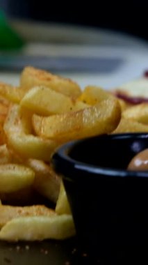 Kahvaltı tabağının izole görüntüsü, siyah tabakta patates kızartmasının yakın görüntüsü, lezzetli fast food yemeklerinin bulanık görüntüsü.