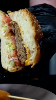 İkiye bölünmüş bir hamburger resmi, lezzetli fast food, iki ekmek arası köfte ve marullu katmanlı hamburger menüsü.