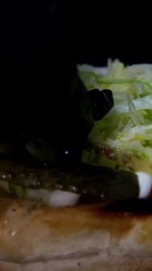 Katmanlı hamburgerin yavaş çekimleri, hamburger içeriğinin düşüşü, lezzetli hamburgerler yapmak, fast food yemeğinin izole edilmiş görüntüsü.