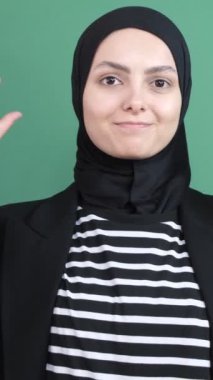 Baş örtüsü vaad ediyor, genç kız dini krom anahtarın önünde, insanlar gerçek konuşuyorlar, gülümseyen kadınlar, izole edilmiş yeşil arka plan