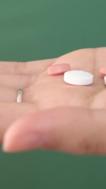 Elinde kapalı haplar, krom anahtarın önünde bir avuç açık hava hapı, renkli haplar