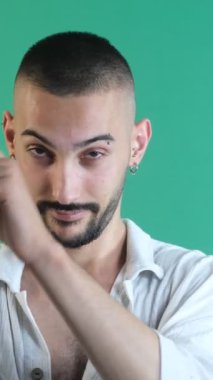 Köşeyi gösteren genç adam, iki eliyle sağ köşeyi gösteren adam, yeşil ekranın önünde çekilmiş yüz ifadeleri resmi.