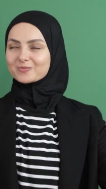 Müslüman kadın geliyor, tesettürlü kız yeşil ekranın önünde işaret parmağı gösteriyor, genç adam her şey yolunda.