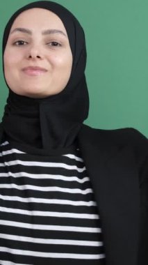 Müslüman kız el aşağı, doğru yönde yeşil ekranın önünde beliren genç kız pozitif.