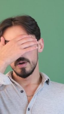 Sıkıcı ve uykulu yeşil ekran, sıkılmış üzgün bakışları olan bir genç, elini kroma anahtarının önüne koyarak yanağını destekliyor.