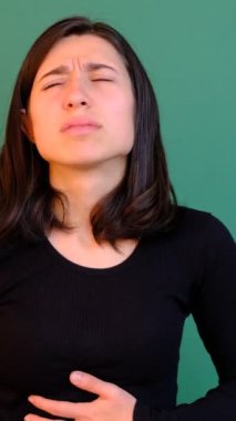 Kadının midesi çok hasta ve yeşil ekranın önünde ağrısı var. Kız bir hastalık ve çok acı çekiyor. Üzüntüyü işaret ediyor.