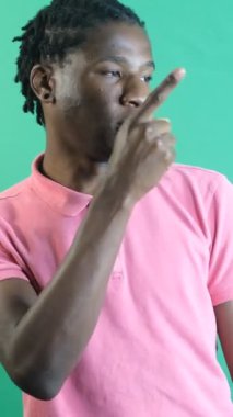 Man points left corner of screen, black teenager pointing to the left of the screen with his left hand, show body language and facial expressions in front of a green screen