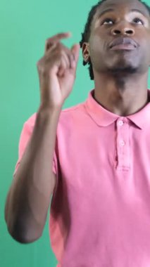 Genç adam parmakla işaret ediyor, siyah genç iki eli ekranın üstünde, yeşil ekranın önünde vücut dilini ve yüz ifadelerini gösteriyor.