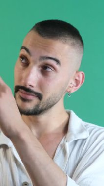 Köşeyi gösteren adam, bir eliyle köşe simgesini gösteren erkek manken, yüz ifadeleri resmi yeşil ekranın önünde çekilmiş.
