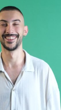 Genç adam mutlu gülüyor, erkek model mutlu bir şekilde gülümsüyor, beyaz tişörtlü erkek model, duygular ve yeşil ekranın önündeki yüz ifadeleri.