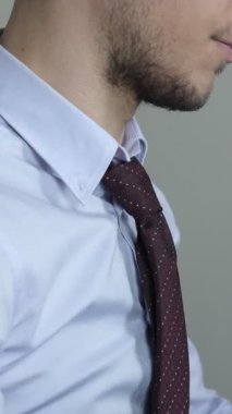 İş adamı kravatıyla oynamaktan yoruldu. Takım elbiseli adam kravatını gevşetmeye çalışıyor. Kravatını gevşetiyor.