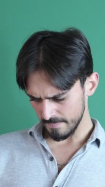 Telefon oyunu gösteren, portre traşsız heyecanlı adam yeşil arka planda izole edilmiş bir cep telefonuyla online oyun oynuyor.