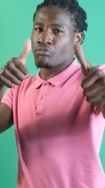İşaret gibi yapan bir adam, iki eliyle işaret yapan siyah bir genç, yeşil ekranın önünde vücut dilini ve yüz ifadelerini gösteriyor.