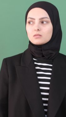 Müslüman kadın üzgün, siyah elbiseli Müslüman kız yeşil ekranın önünde kendine sarılıyor, genç adam mutsuz, kız kötü hissediyor, ifade üzgün.