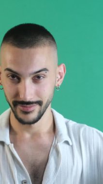 İşaret dilini seven bir adam, iki eliyle işaret yapan genç bir adam, yeşil ekranın önünde vücut dilini ve yüz ifadelerini gösteriyor.