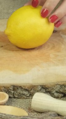 Limonu bıçakla dilimleyen bir kadın, sunum tabağıyla dilimleyen bir kadın, on tahta kesme tahtasının üzerinde bıçakla sarı limonları ikiye bölen bir kadın.