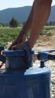 Closing the water pump, close up of blue water filter, view of agricultural irrigation equipment, farmer closing the lid of the blue water pump