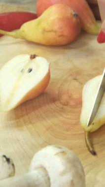 Armutları servis tabağında bıçakla kesme, tematik bir doğal ürün masasında meyve kesme, ahşap sunum tabağında kesme.