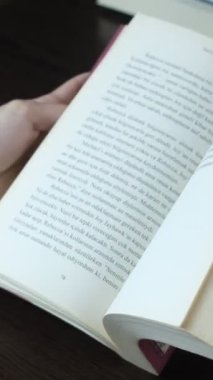Elindeki kitabın sayfalarını çeviren, bir roman okumak için sayfaları çeviren, kitabın sayfalarını hızlıca inceleyen kızın görüntüleri.