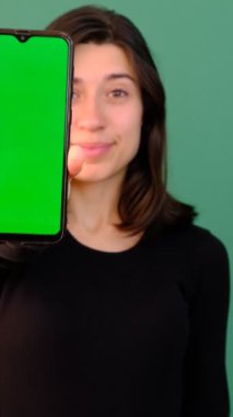 Yeşil ekranlı telefon gösteren, gülümseyen, telefon ekranını gösteren, yeşil ekran izole yeşil arka planlı akıllı telefon.