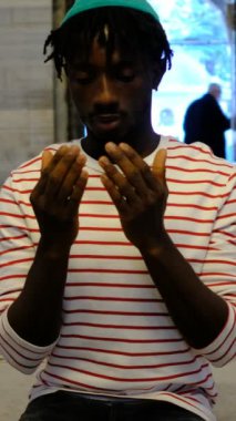 Afrikalı genç siyahi adam camide oturmuş elleri açık Allah 'a dua ediyor. Müslüman erkekler camiye ibadet etmeye gidiyor.