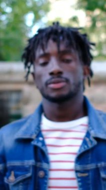 Siyahi genç adam parkta parmağını kameraya doğru uzatarak 