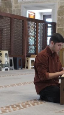 Bir genç adam, camiinin içinde Kur 'an' ı, farklı açılardan okuyarak ve onunla beraber Kur 'an' ın ayetlerini okuyarak şöyle der: 