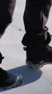 Kardaki adımların yakın görüntüsü, karda yürüyen bir adamın ayak izlerini takip eden görüntüler.