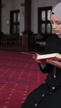Kafiyeli kadın caminin içinde Kuran okuyor, kürsüde el-Kuran 'a dua ediyor, İslam' ın kutsal kitabını okuyor, Müslüman kadın Kuran 'dan dizinde dua ediyor, Mescid' in içinde.