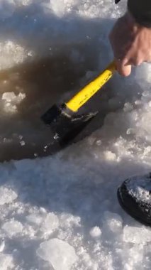Buz Keşfi, buzun üst katmanını kırıp donmuş bir gölde baltasıyla suya ulaşan ve kendine bir su birikintisi oluşturan genç adamın konsept görüntüsü.